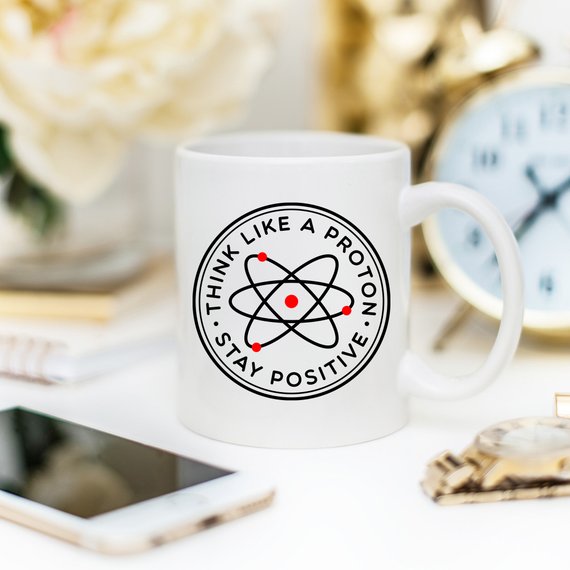 Tazza Mugffins Chimica 'Be A Proton. Stay Positive'. Tazza Da 350 Ml In Ceramica Bianca, Lavabile In Lavastoviglie E Microonde. Regalo Divertente Per Geek, Ingegneri E Amici.